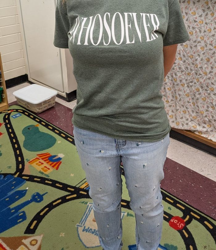 A customer wearing a green WHOSOEVER T-shirt, photographed from below the collar in her classroom.