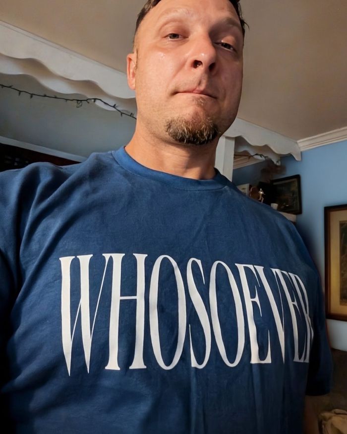 A blue WHOSOEVER T-shirt being worn indoors.
